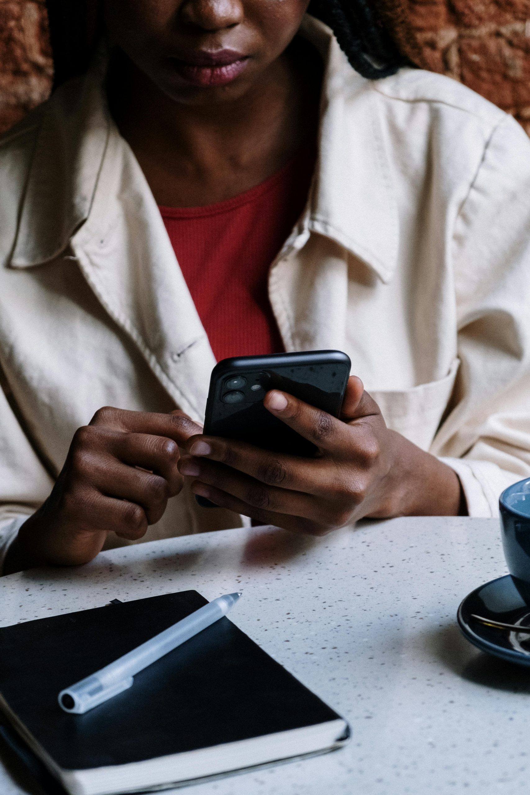 An African American woman using her smartphone at a cafe, focusing on technology and communication.