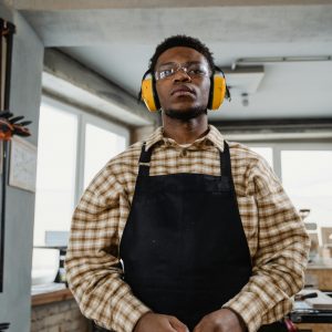 Skilled carpenter working in a workshop with protective gear and equipment.