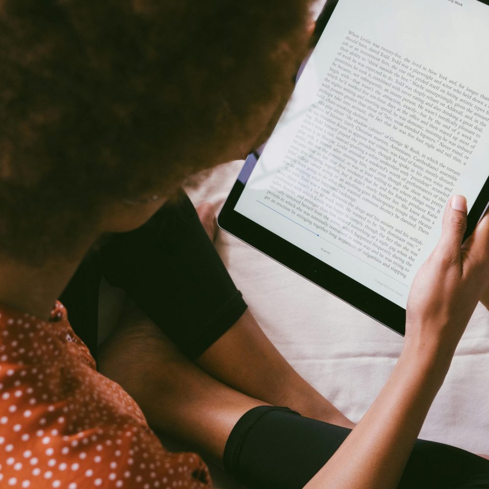 Woman reading an ebook on a tablet indoors, relaxed modern lifestyle.