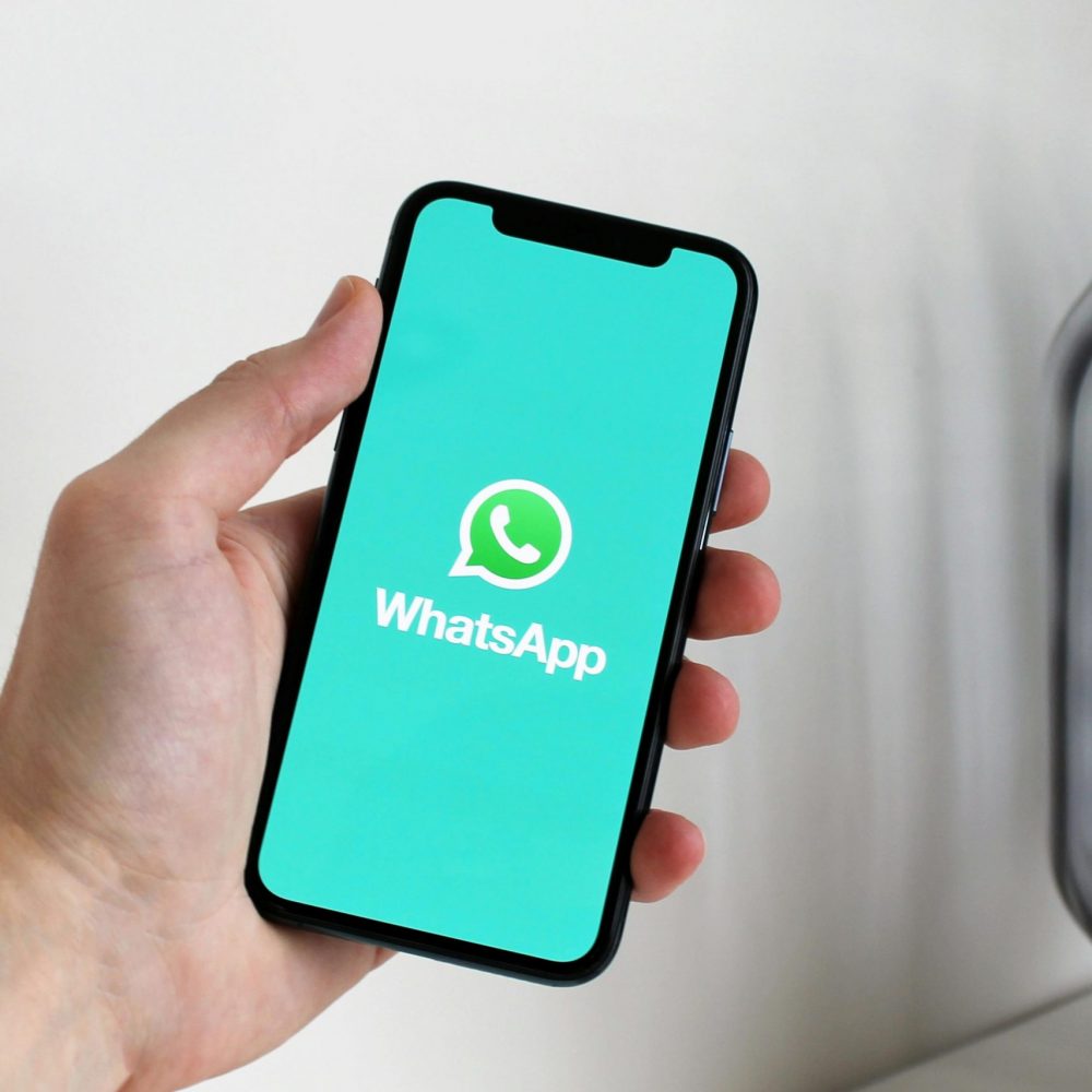 Close-up of a hand holding a smartphone displaying the WhatsApp app screen.