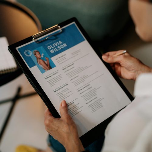 An HR professional reviews a resume on a clipboard during an office meeting.