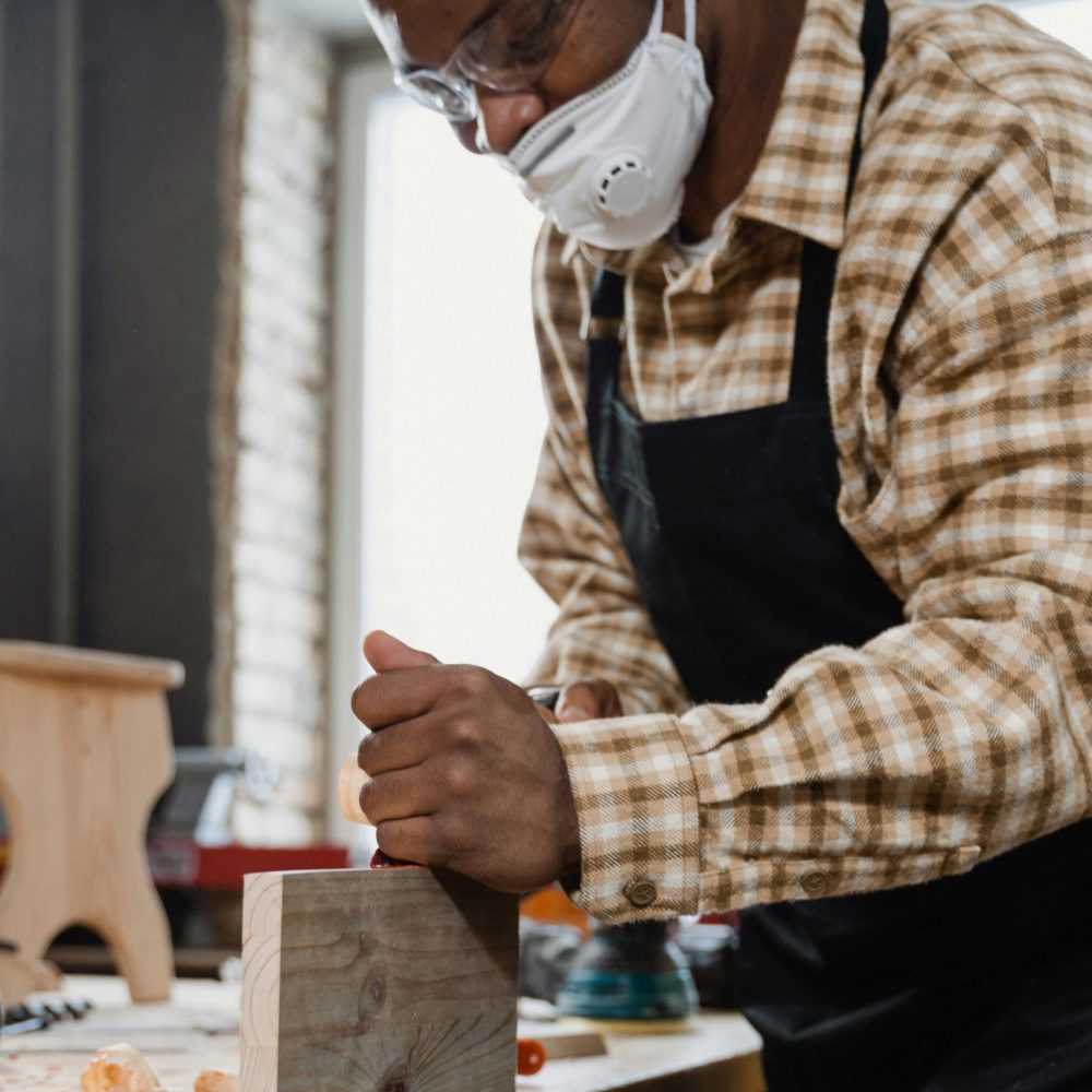 A focused carpenter works on a wooden project in a well-equipped workshop.