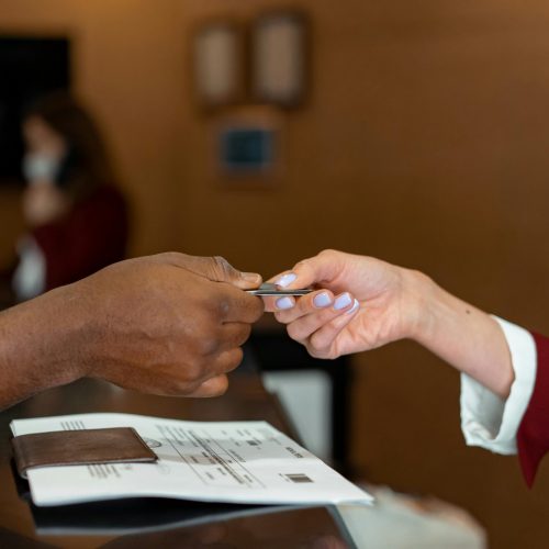 Close-up of a hotel receptionist receiving a credit card from a guest, highlighting a transaction at check-in.